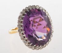 An amethyst and diamond cluster ring, claw set to the centre with an oval-cut amethyst,