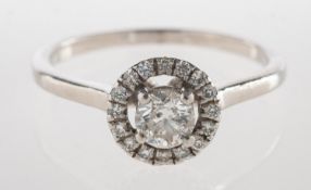A modern diamond halo ring, claw set and raised to the centre with a brilliant-cut diamond,
