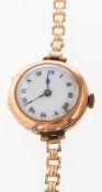 A 9K gold lady's wristwatch having a round white enamel dial with black Roman numerals,