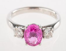 A pink sapphire and diamond three stone ring, claw set to the centre with an oval-cut pink sapphire,