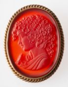 A 9ct gold cameo brooch, an oval orange hardstone carved plaque depicting a maiden,