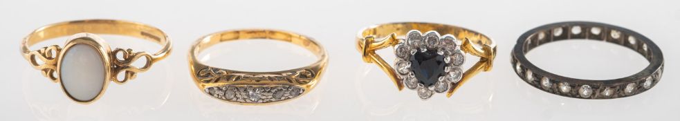 A group of four rings, including a full eternity style ring set with circular-cut paste stones,