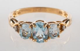 A three stone ring, claw set with three oval-cut blue stones, possibly aquamarine and/or blue topaz,