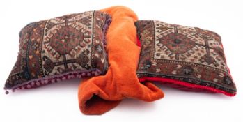 Two cushions, upholstered in fragments from Turcoman carpets together with a machine made throw.