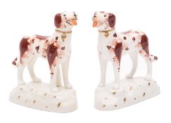 A pair of Staffordshire pottery dogs modelled standing four square on rustic bases painted facial