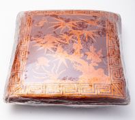 A Chinese tooled leather pillow decorated with a bat and two birds amongst bamboo,