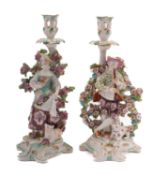 A pair of Chelsea-Derby candlestick figures of a shepherd and shepherdess with bocage backgrounds,