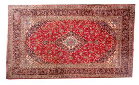 A Kashan carpet, the rose cartouche field with a central indigo,