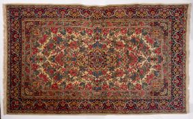 A Kirman rug, the ivory cartouche field with a mille fleur design,