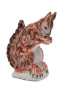 An English porcelain squirrel, modelled on its haunches eating a nut, on rustic mound base,