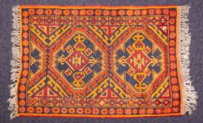 A Kurdish rug, the field in orange colours with twin lozenge medallions and geometric designs,