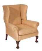 An upholstered and stained wood wingback armchair in Quen Anne taste,