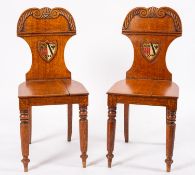 A pair of George IV carved oak hall chairs,