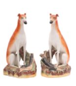 A pair of Staffordshire greyhounds, modelled in seated posture with a hare at foot, on rustic bases,