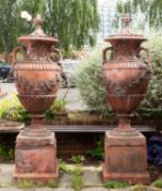 A pair of substantial faux terracotta garden urns on plinths,