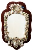 A Plaue porcelain girandole mirror the arched frame encrusted with flowers, foliage and six putti,
