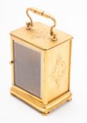 A gilt-brass clock case with engraved decoration to the sides and with a swing handle,