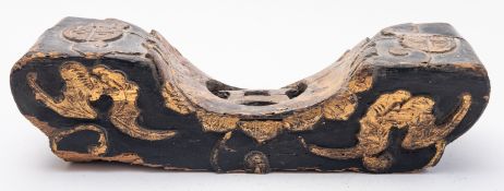 A Chinese carved wooden pillow picked out in gold with bats, cash motif and Shou medallions,