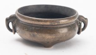A small Chinese bronze tripod censer of circular form with cast lug ring handles,
