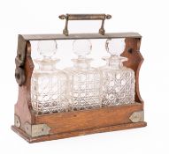 An oak and metal mounted tantalus, late 19th /early 20th century; the toprail with handle,