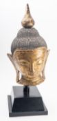A Burmese wood and dry gilt lacquer Buddha head with serene visage and pendulous ear lobes,