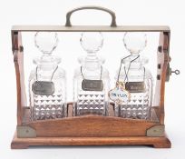 An Edwardian oak and brass Betjemann's Patent tantalus,