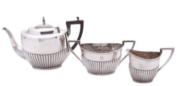 An Edwardian three-piece silver tea set, of oval form, with part-fluted bodies,
