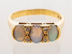 An 18ct gold opal and diamond ring, set with three oval opal cabochons,