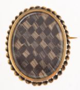 An antique mourning brooch, an oval brooch with a checkerboard of plaited hairwork,