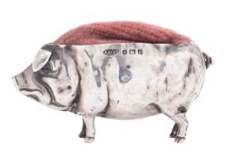An Edwardian novelty silver pin cushion, in the form of a pig, with a pink material lining,