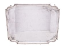 A George V silver salver, of shaped rectangular outline, with incurved corners and on four legs,