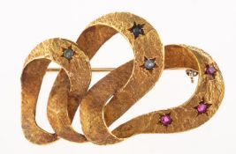 An openwork ribbon brooch, of abstract form with textured finish,