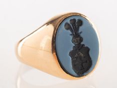 A carved onyx intaglio ring, the oval onyx plaque carved with a family crest,