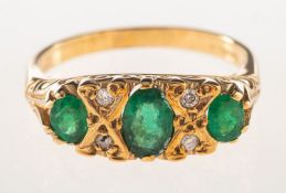 A 9ct gold emerald and diamond gypsy ring, set with three oval-cut emeralds,