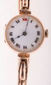 A 9K gold lady's wristwatch the round white dial having black and red Roman numerals and blued
