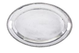 A George V silver two handled tea tray of oval form, with a cotton reel rim and cut handles,