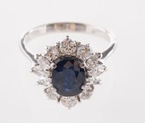 A sapphire and diamond cluster ring, claw set to the centre with an oval-cut dark blue sapphire,