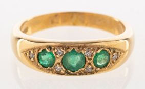 A 9ct gold emerald and diamond ring, grain set with three circular-cut emeralds,