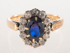 A cluster ring, claw set to the centre with an oval-cut synthetic dark blue sapphire,