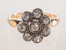 A diamond daisy ring, of flowerhead form, grain set to the centre with an old-cut diamond,