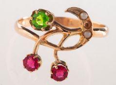 A floral and foliate designed ring, claw set with two circular-cut red paste stones,