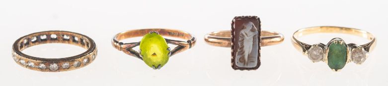 A group of four rings, including a 9ct gold three stone ring, claw set with an oval-cut green stone,
