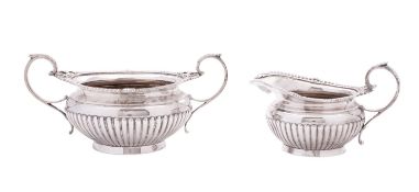 An Edwardian silver sugar bowl & matching milk jug, squat circular form, with fluted lower bodies,