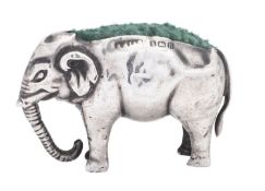 A George V novelty silver pin cushion, in the form of an elephant, with a green material lining,