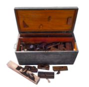 A collection of woodworking planes in a wooden tool chest.