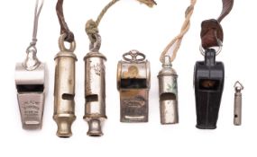 Two 20th Century Acme whistles together with three other metal whistles and a plastic example.