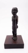 An African carved and stained hardwood model of a captive male, 20th century; portrayed standing,