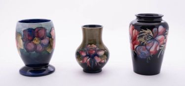 Three Walter Moorcroft pottery vases comprising a squat vase tube lined in the Columbine pattern on
