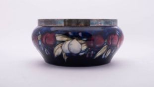 A William Moorcroft pottery bowl, tube lined in the Plum pattern reserved on a blue ground, with e.