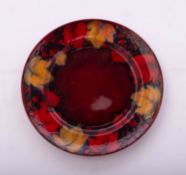 A William Moorcroft pottery plate, tube lines in the Flambé Leaf and Fruit pattern, 21cm diameter,
